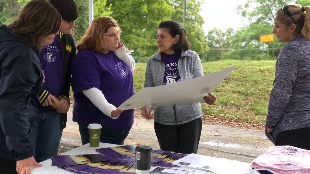 People looking over A Safe Place blue print plans for a project